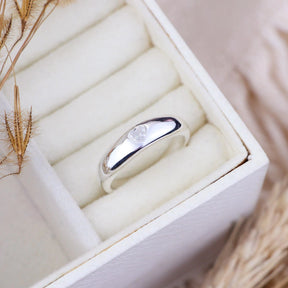 Anillo de plata con banda lisa y corazón central.