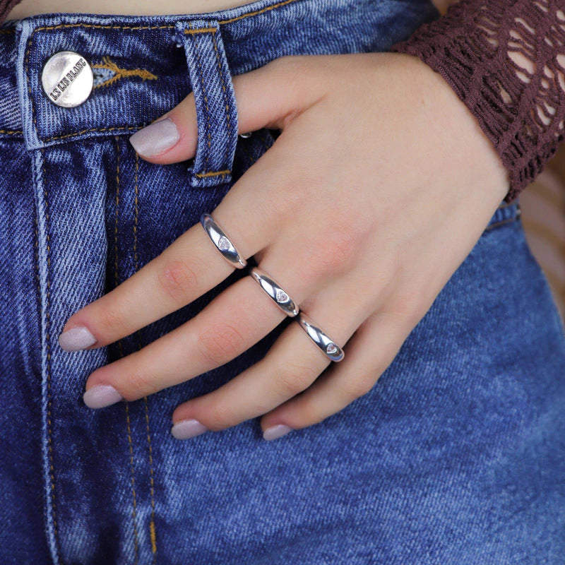 Anillo de plata con banda lisa y corazón central.